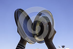 Woman hands banging pot lids against blue sky. Protest against the government measures. Banging pots and pans from the