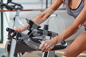 Woman hands on a bar stationary bike the gym