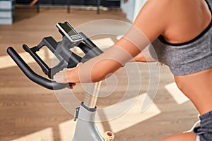 Woman hands on a bar stationary bike the gym