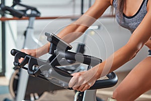 Woman hands on a bar stationary bike the gym photo