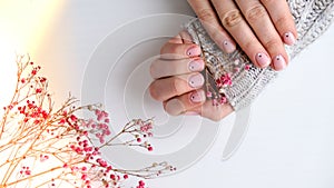 Woman hands with beautiful nude manicure holding delicate pink Gypsophila or baby's breath flowers. Female Manicure