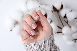 Woman hands with beautiful nude manicure holding delicate white cotton flower. Female Manicure, natural look. Nails care. Self