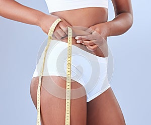 Woman, hands and belly with tape measure for weight loss and tummy tuck in underwear on a blue studio background