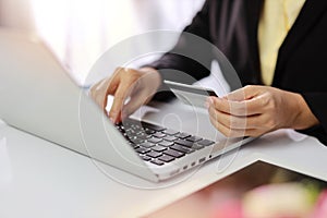 Woman hands in black suit sitting and holding credit card and using laptop computer on table for online payment or shopping online