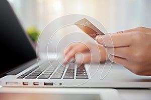 Woman hands in black suit sitting and holding credit card and using laptop computer on table for online payment or shopping online