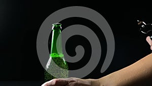 Woman hands with a bottle of beer with open on a black background, slow motion