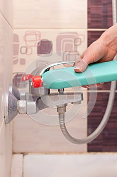 Woman hands with bottle of cleaning detergent for bathroom applies a scour to the metal water tap