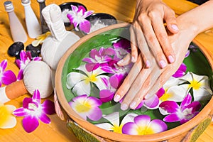 Woman hands with a bowl of aroma spa water on wooden table