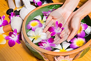 Woman hands with a bowl of aroma spa water on wooden table