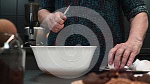 Woman hands break eggs to prepare traditional dough. Egg falls into bowl with prepared flour and dough ingredients. Female is brea