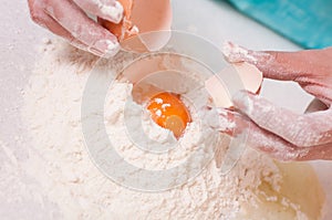 Woman hands breaking egg into flour