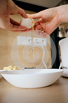 Woman hands breaks chicken eggs in a bowl in the kitchen.