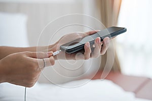 Woman hands charging battery in mobile smart phone in the bedroom at home. Technology, multiple sharing and lifestyle concepts