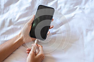 Woman hands charging battery in mobile smart phone in the bedroom at home. Technology, multiple sharing and lifestyle concepts