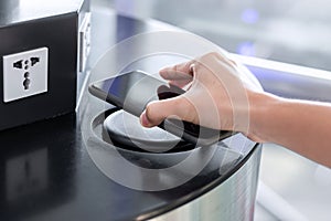 Woman hands charging battery in mobile smart phone by wireless charger at international airport terminal. Technology, multiple