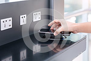 Woman hands charging battery in mobile smart phone by wireless charger at international airport terminal. Technology, multiple