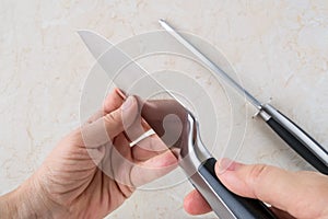 Woman hands checking the blade of professional chef knife after using the sharpening steel. Modern kitchen utensils made of high