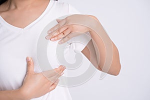 Woman hands checking lumps on her breast for signs of breast cancer on gray background, health care concept