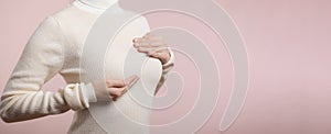 Woman hands checking lumps on her breast for signs of breast cancer on pink background. Healthcare concept