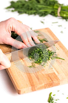 Woman hands chopping the dill on the cutting board
