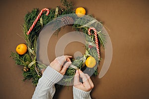 Woman hands with Christmas wreath on brown background. Top View