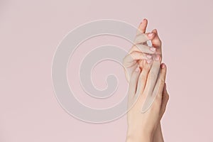 Woman hands with clean skin and nails with pink polish manicure on pink background. Nails care and beauty theme.