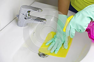 Woman hands cleaning sink with spray and sponge