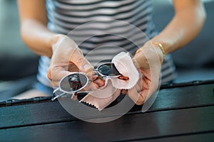 Woman hands cleaning and wiping sun glasses with micro fiber wipe