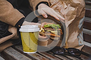 woman hands close up holding burger with coffee cup. fast food