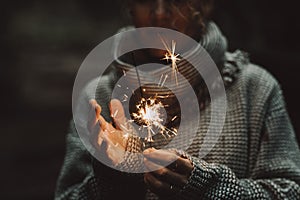 Woman hands close up holding sparkler light to celebrate alone in the dark. Day dreaming female people with fire lights in the