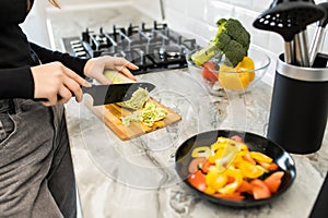 Woman hands cut vegetables for salad in the kitchen at home