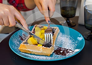 Woman hands cutting belgium waffles with fruite. Woman hands with cutlery
