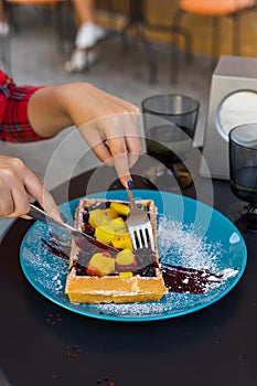 Woman hands cutting belgium waffles with fruite. Woman hands with cutlery