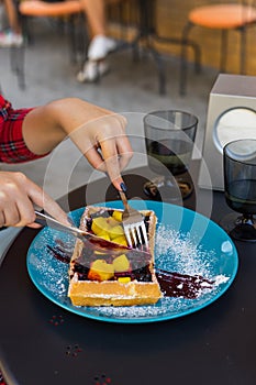 Woman hands cutting belgium waffles with fruite. Woman hands with cutlery