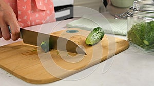 Woman hands cutting ends of cucumbers to cook pickles on kitchen at home.