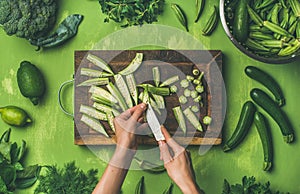 Woman hands cutting green vegetables and greens, top view