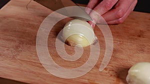 woman hands cutting onion closeup on wooden board