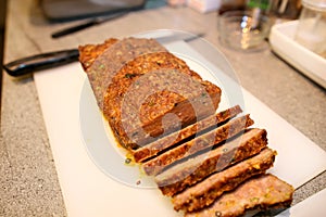 Woman hands cutting piece of meatloaf, she prepare for tasting of food at kitchen. Chef cutting meatloaf with knife on board.