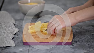 Woman hands cutting pineapple on small pieces.