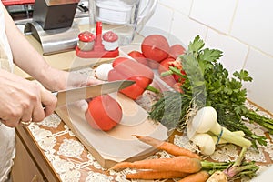 Woman hands cutting ripe tomato