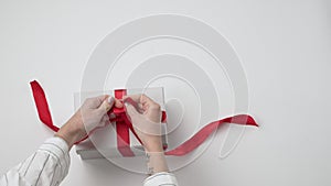 Woman hands decorates present, tie a bow on gift box