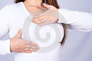 Woman hands doing breast self exam for checking lumps and signs of breast cancer on grey background. Medical, healthcare for