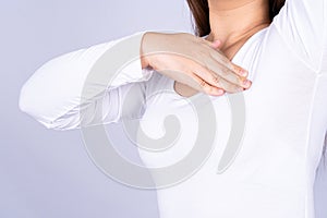 Woman hands doing breast self exam for checking lumps and signs of breast cancer on grey background. Medical, healthcare for