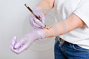 Woman hands drawing on an arm with eye pensil