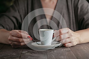 Woman hands with espresso on a wood table
