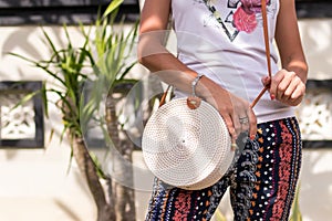 Woman hands with fashionable stylish white rattan bag. Tropical island of Bali, Indonesia. Rattan handbag.