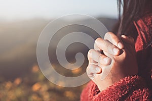 Woman hands folded in prayer in beautiful nature background