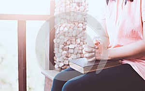 Woman hands folded in prayer on a Holy Bible