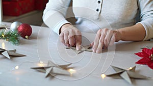 Woman hands folding origami paper star for Christmas decoration