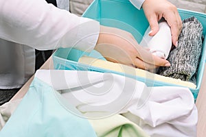 Woman hands folds her clothes and puts them in blue storage box. Vertical storage of clothing, tidying up, room cleaning